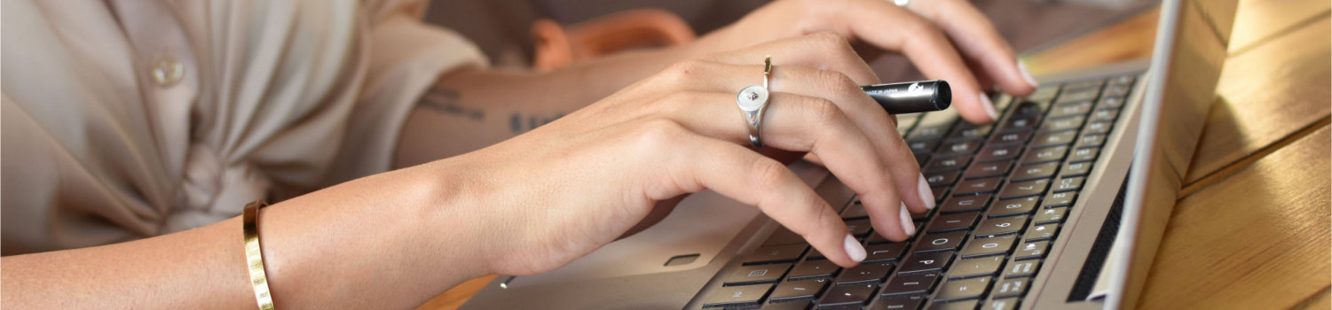 Closeup shot of a young female working on her laptop and having a croissant in a cafe